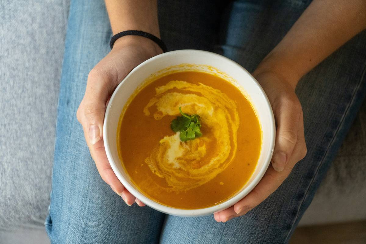 Low-Sodium organic vegetable soup simmering in cast-iron pot with fresh herbs