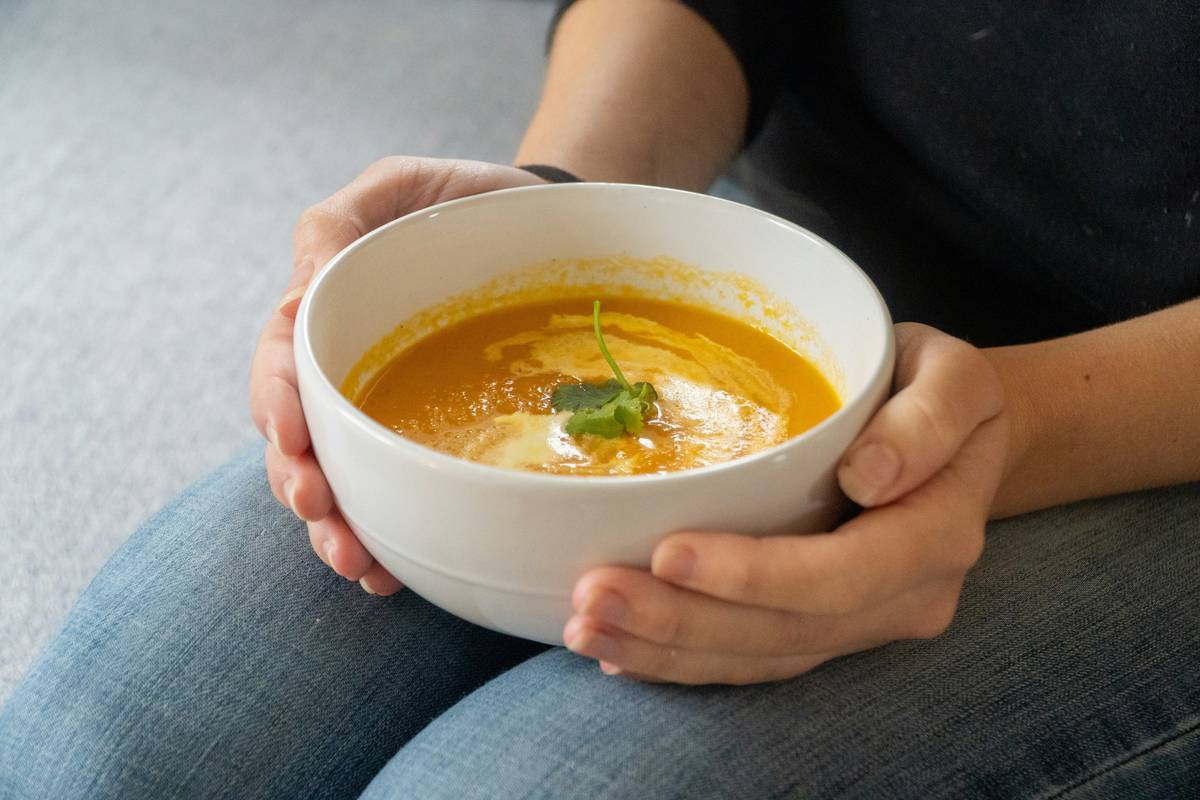 Steaming bowl of golden organic vegetable soup labeled as Comfort Foods